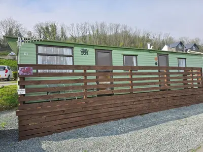 a green trailer behind a wooden fence at Homely 2 Bedrommed Mobile Home E1 in Aberystwyth