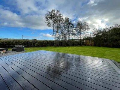 a wooden deck in a yard with a lawn at The Pod at Gerycoed in Llangadog