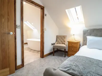 a bedroom with a bed and a tub and a chair at Gaerau Bach in Llanbedr