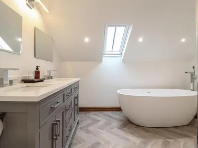 a white bathroom with a tub and a sink at Gaerau Bach in Llanbedr
