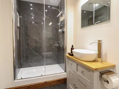 a bathroom with a shower and a white sink at Gaerau Bach in Llanbedr