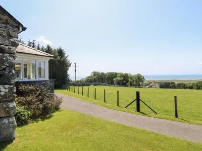 a house with a fence next to a field at Ysgubor Newydd Parc Isaf in Dyffryn