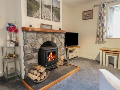 a living room with a stone fireplace and a tv at Ysgubor Newydd Parc Isaf in Dyffryn