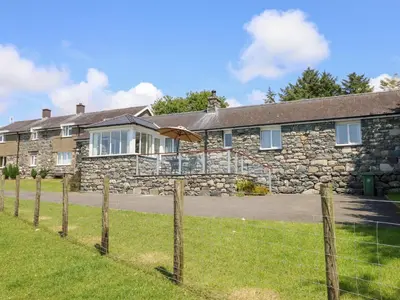 a stone house with a fence in front of it at Ysgubor Newydd Parc Isaf in Dyffryn