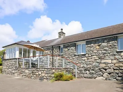 a stone house with an umbrella in front of it at Ysgubor Newydd Parc Isaf in Dyffryn