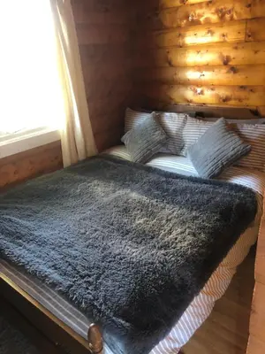 a bed in a log cabin with a blanket on it at Misty Mountain Log Cabin - Trawsfynydd in Trawsfynydd