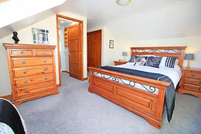 a bedroom with a large wooden bed and a dresser at Artist's Cottage in Penrhyndeudreath