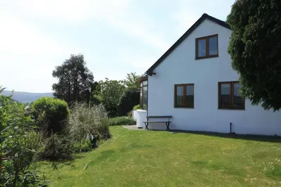 a white house with a bench in the yard at Artist's Cottage in Penrhyndeudreath
