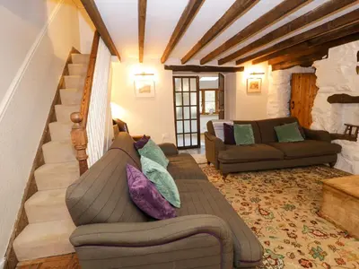 a living room with a couch and a staircase at Glandwr Cottage in Llanbedr