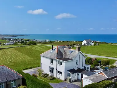 an aerial view of a white house with the ocean in the background at Glynmor in Harlech