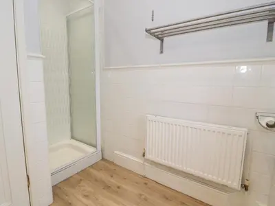 a bathroom with a walk in shower and a glass door at Glynmor in Harlech