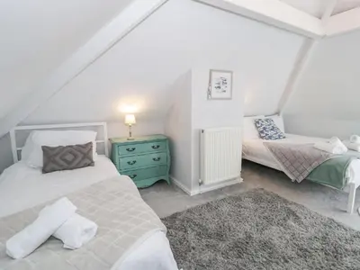 a bedroom with two beds and a green dresser at Glynmor in Harlech