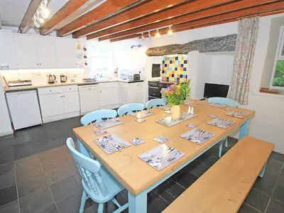 a large wooden table with blue chairs in a kitchen at The Farmhouse in Llanbedr
