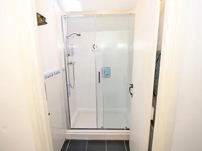 a shower with a glass door in a bathroom at The Farmhouse in Llanbedr