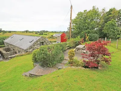 a garden with a picnic table and a barn at The Farmhouse in Llanbedr