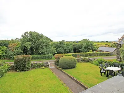 a garden with tables and chairs and bushes at The Farmhouse in Llanbedr