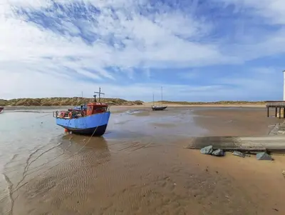 a blue boat sitting in the water on the beach at Sandpiper Apartment in Barmouth