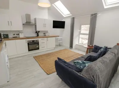 a living room with a couch and a kitchen at Sandpiper Apartment in Barmouth