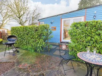 a backyard with a blue house and a table and chairs at Shed Your Blues in Hereford