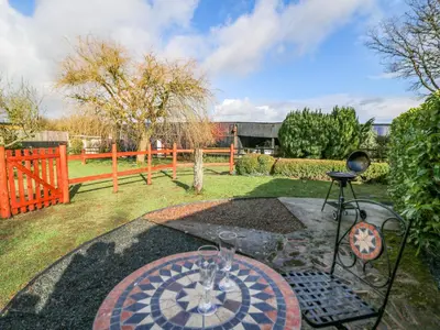 a garden with a table and a stone patio at Shed Your Blues in Hereford