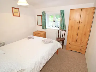 a bedroom with a bed and a chair and a window at Y Stabl The Old Stable in Llanbedr