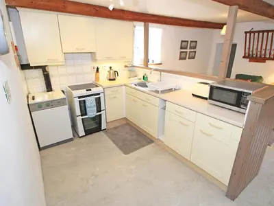 a large kitchen with white cabinets and appliances at Y Stabl The Old Stable in Llanbedr