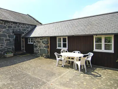 a patio with a table and chairs in front of a building at Y Stabl The Old Stable in Llanbedr