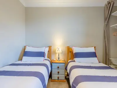 a bedroom with two beds and a lamp on a night stand at Bettys Cottage in New Quay