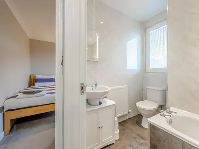 a bathroom with a sink and a toilet and a bed at Bettys Cottage in New Quay