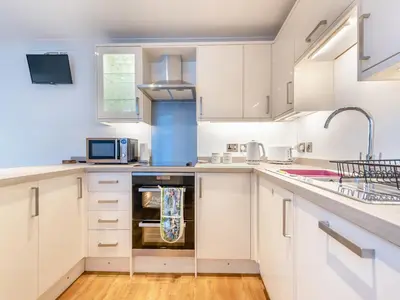 a kitchen with white cabinets and a sink at Bettys Cottage in New Quay