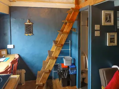 a wooden staircase in a room with a blue wall at Y Smithy - Uk49022 in Llanybydder