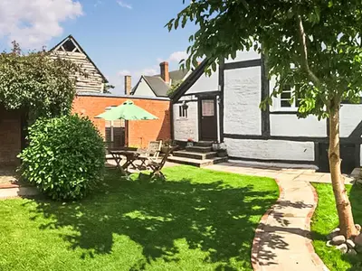 a yard with a table and an umbrella at The Cottage in Weobley
