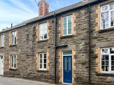 an old brick building with a blue door at Cosy Cwtch in Hay-on-Wye