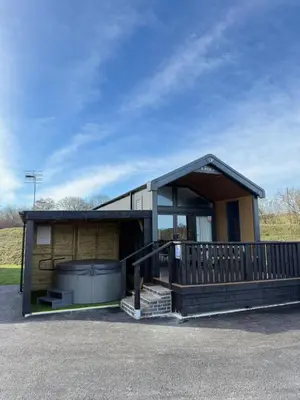 a small house with a porch and a large at Lodges at Moody Meadows in Llanarth