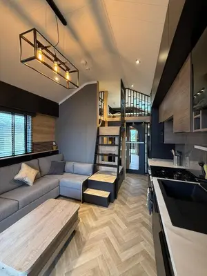 a living room with a couch and a staircase in a tiny house at Lodges at Moody Meadows in Llanarth