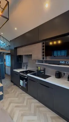 a large kitchen with black cabinets and a stove at Lodges at Moody Meadows in Llanarth