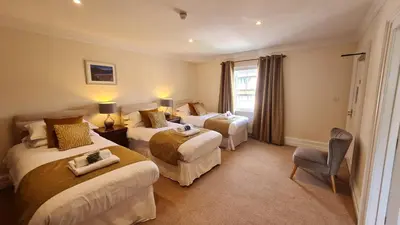 a hotel room with two beds and a chair at The Trewythen in Llanidloes