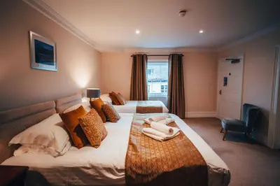 a hotel room with two beds and a chair at The Trewythen in Llanidloes