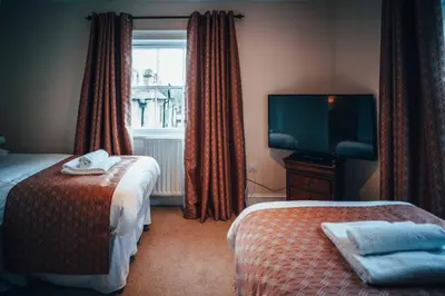 a hotel room with two beds and a flat screen tv at The Trewythen in Llanidloes