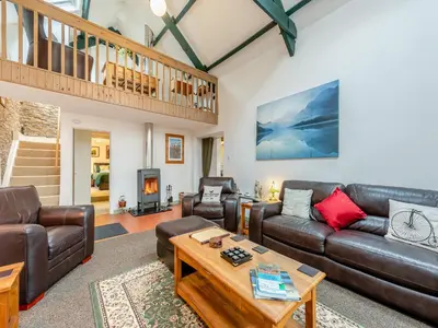 a living room with leather couches and a wooden table at Rhydyfran Coach House in Cribyn