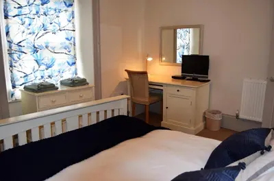 a bedroom with a bed and a desk and a mirror at Awel Mor Holiday Apartment in Aberystwyth