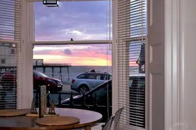 a room with a table and a window with a view of the ocean at Awel Mor Holiday Apartment in Aberystwyth