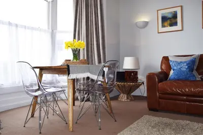 a living room with a table with chairs and a couch at Awel Mor Holiday Apartment in Aberystwyth