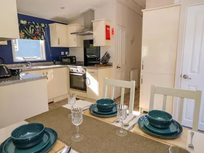 a kitchen with a table with plates and glasses on it at 98 The Heron in New Quay