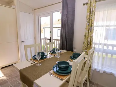 a dining room with a table and chairs and a window at 98 The Heron in New Quay