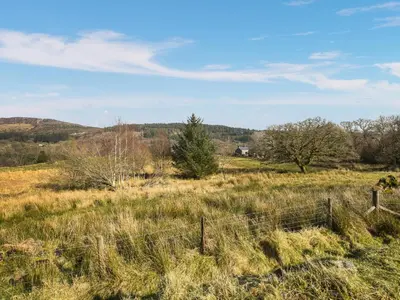 a field of grass with a fence in the foreground at Aberserw Cottage in Trawsfynydd