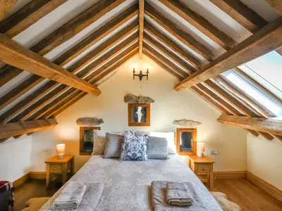 a bedroom with a large bed with wooden beams at Aberserw Cottage in Trawsfynydd