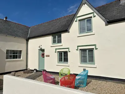 a white house with colorful chairs in front of it at Tower Farm Holidays in Llangollen