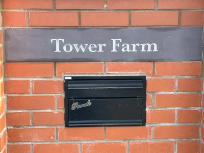 a sign for a tower farm on a brick wall at Tower Farm Holidays in Llangollen