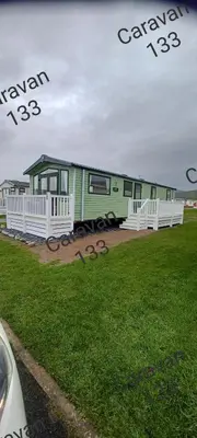 a green train is parked in a field at Caravan 133 snowdon summit 090 in Barmouth
